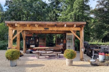 Binnenplaats met eettafels grillplaat en pizzaoven op vakantiedomein La-Bastide in de Haute-Vienne